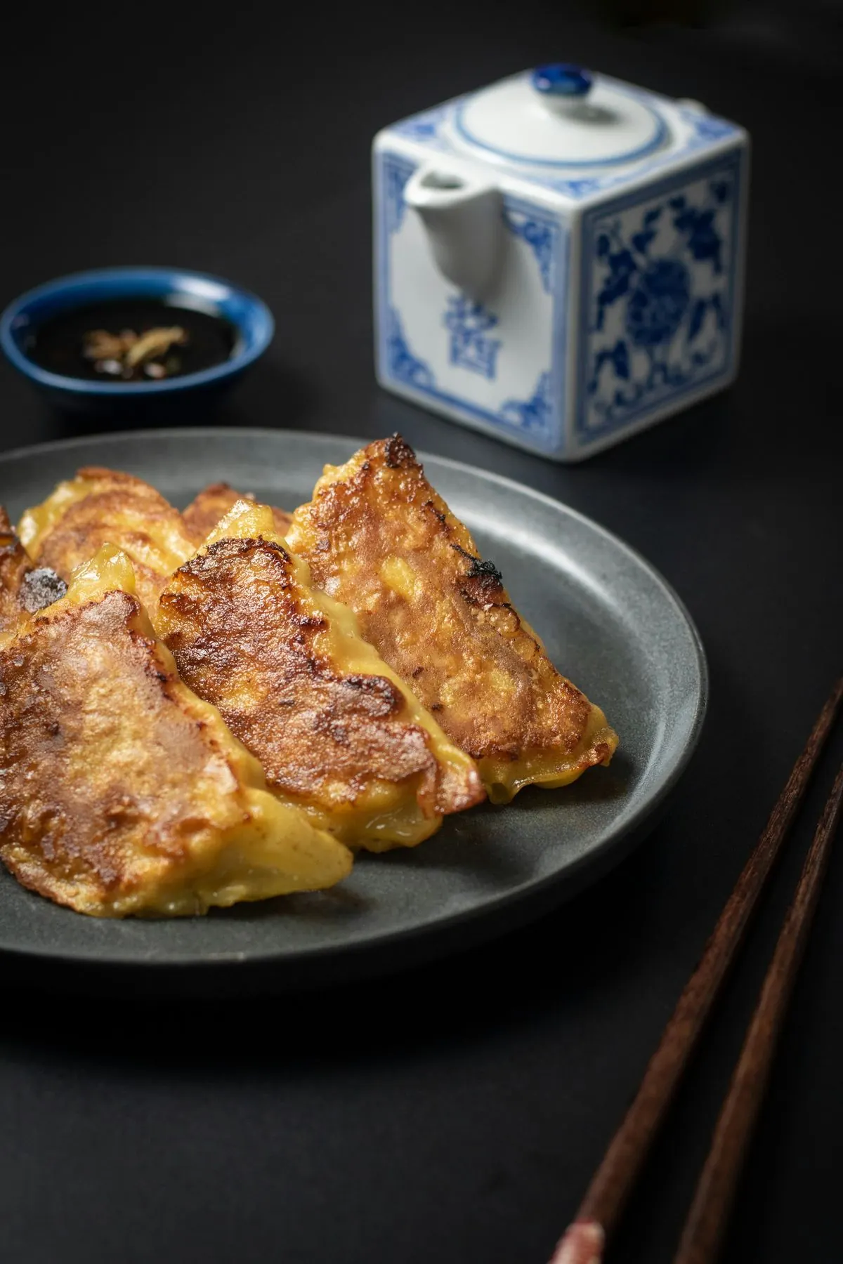 검은 접시 위 노릇하게 지진 만두와 청화백자 주전자