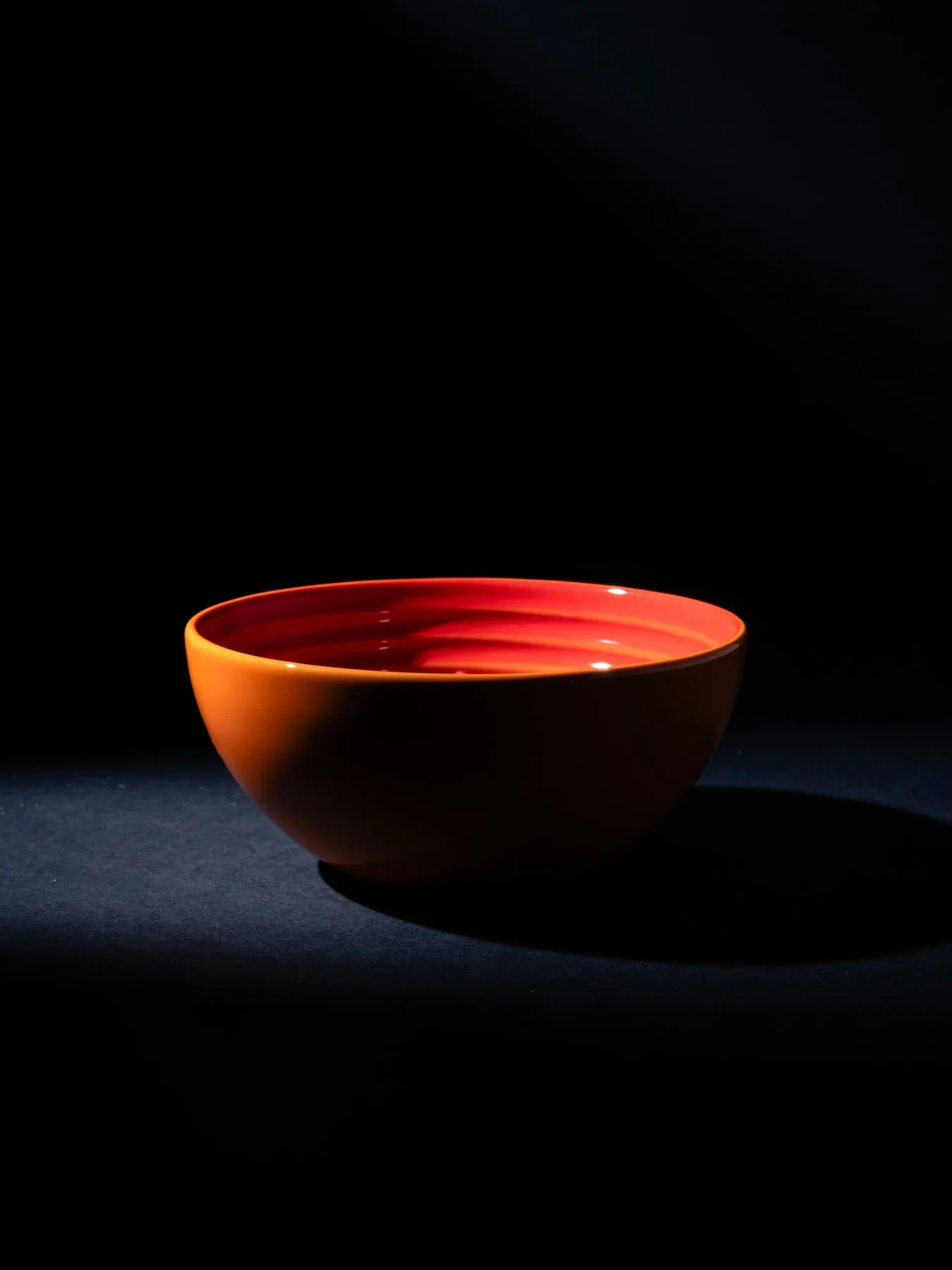 검은 배경 위 붉은 옻칠 그릇 하나